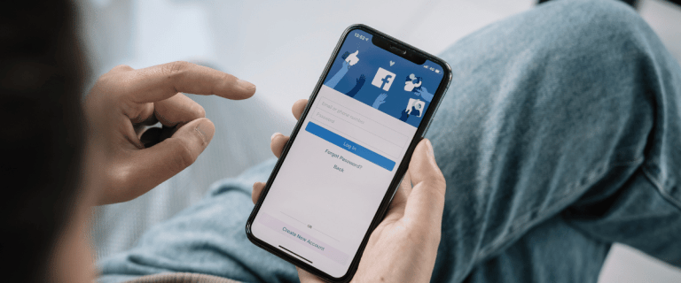 Grow your small business on social media - A person holding a mobile phone showing a Facebook login page