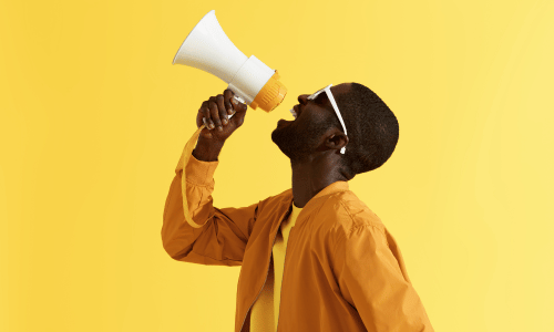 how_to_grow_social_media_of_your_small_business_blog_post_picture_2 A man making an announcement with a megaphone on a yellow background
